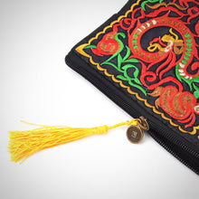 The image is a close-up of the Double Dragon Embroidered Clutch. Features: Bright yellow tassel with small coin detail on the zipper.