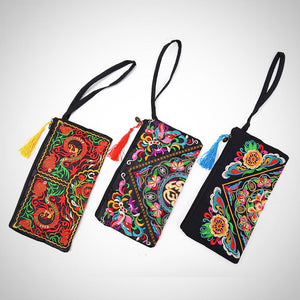 The image is of all three available patterns side by side for the Embroidered Clutch. Features: The material is for interior and exterior is cotton, the style is a day clutch, the closure is a zipper, the size is approximately 15cm x 27cm, no straps, interior compartment, embroidered pattern, tassel on the end of the zipper.